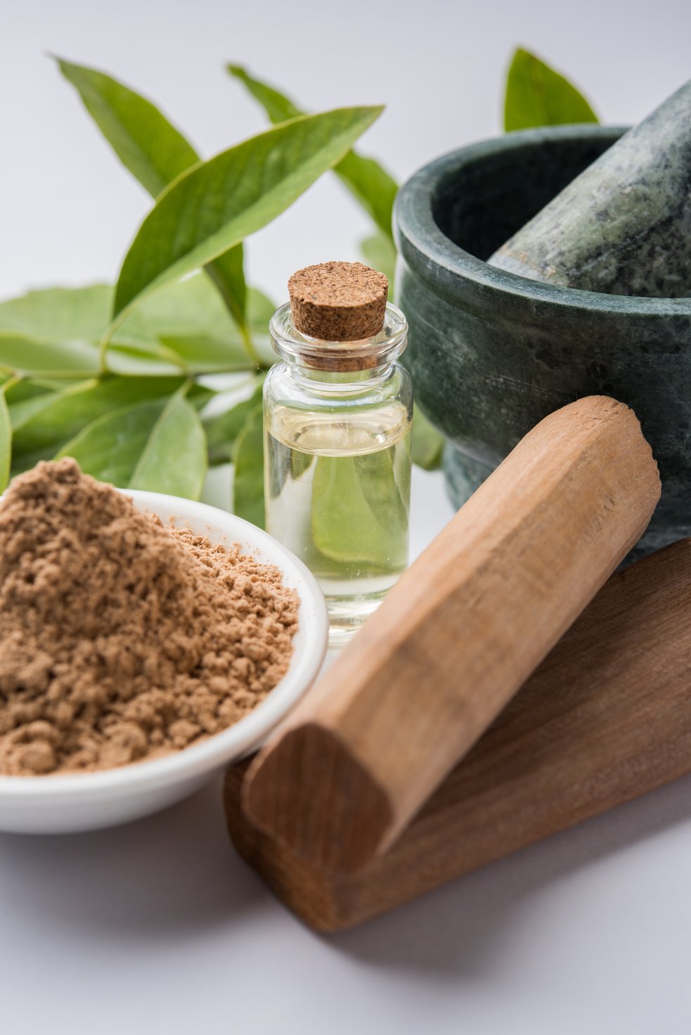 Chandan or sandalwood powder with traditional mortar, sandalwood sticks, perfume or oil and green leaves. selective focus